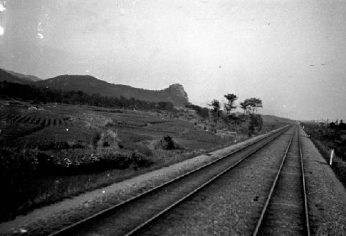 Railroad tracks, fields, distant hills