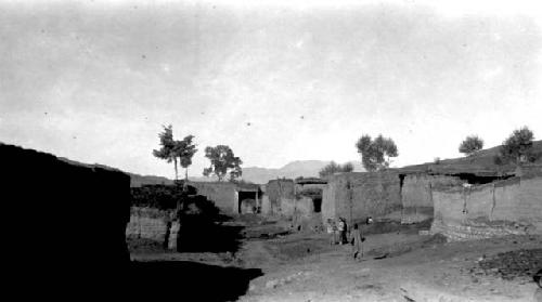 Low lying buldings and wall, people on road