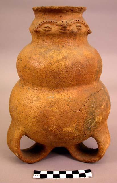Pottery jar with 3 loop legs, 2 anthropomorthic faces on neck.  Light brown, pro