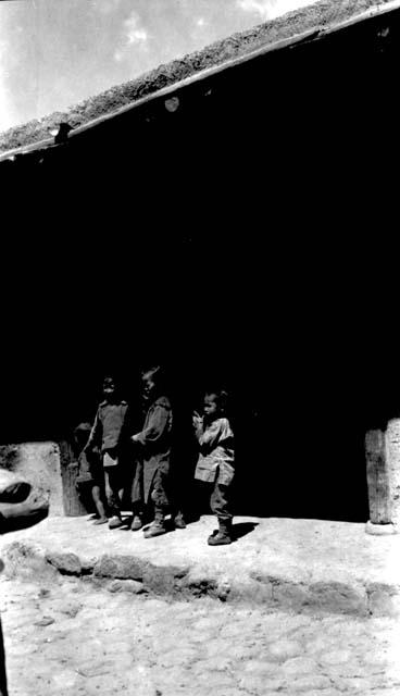 Children standing under eaves of building