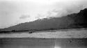 Boats on distant shore of river, mountainour background