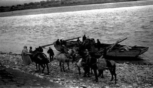 Boat moored at river edge, people and horses on shore