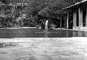 Waterfall flowing into pool, building at right