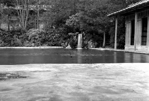Waterfall flowing into pool, building at right