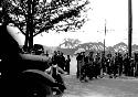 Car and group of people on road, one holding umbrella