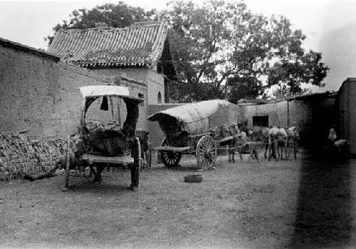 Horse drawn carts outside walled building