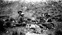 Men sitting at campfire on rocky hillside, horse in background