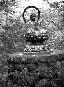 Seated Buddha statue on stone platform in garden