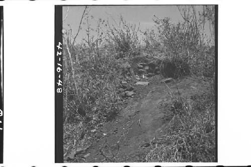 Small pit dug in south side near top of mound showing construction of lajas and