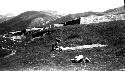 Person laying cloth in field, walled structure behind