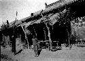 People standing in front of tables and benches under building awning