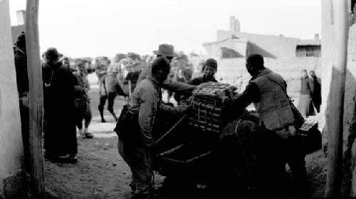 People loading a camel with boxes