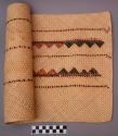 Mat, woven plant fiber, black and rust geometric design, partially rolled