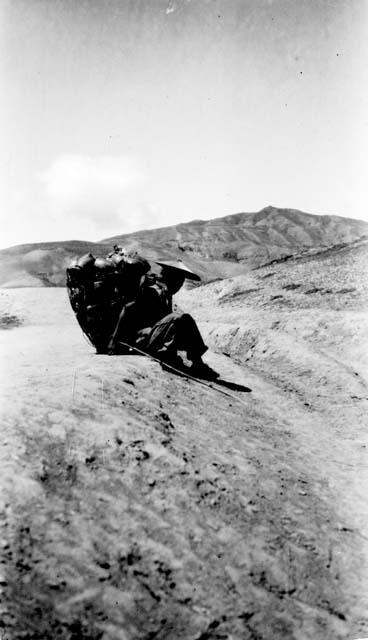 Person with pack on back resting in mountains