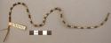 Necklace of small white and brown beads of shell strung on grass
