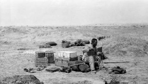 Man sitting on boxes in desert