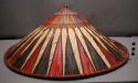 Conical hat of natural leaves with red strips radiating from the +