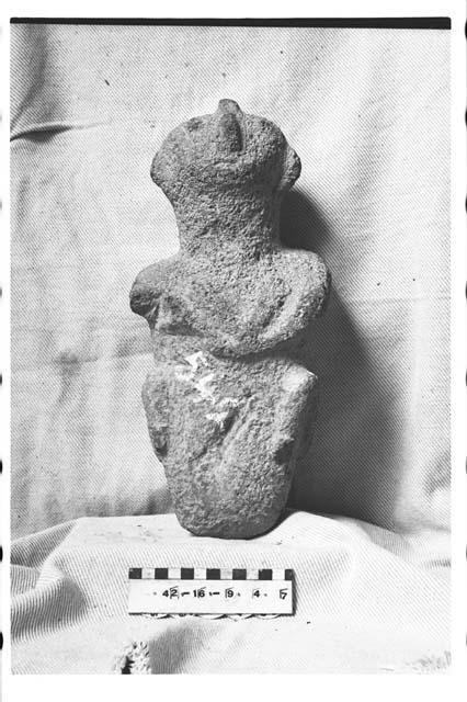 Carved stone human figure resembling "death sculpture". Grey scoriaceous stone.