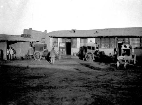 Person walking by carts toward house in courtyard