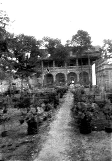 Arched building at end of narrow dirt path through garden