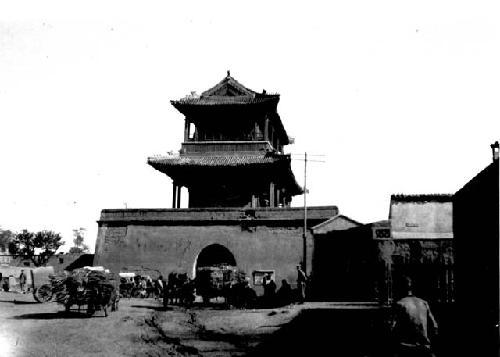 Arched gate with tower, carts gathered outside