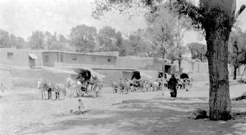 People and ponies with carts by buildings