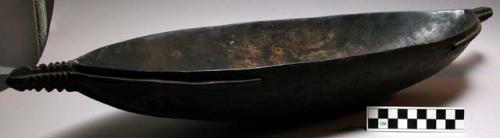 Elongated oval bowl, stained dark brown, tapered carved handles either end. Flan