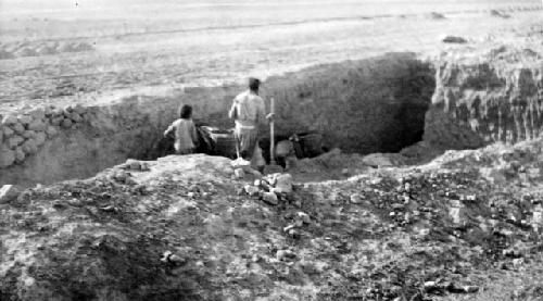 People with shovels standing in pit in desert