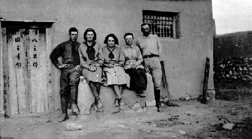 Five people posing outside of building