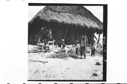 Children in front of thatched-roof house