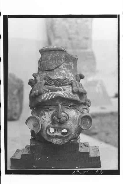 Large pottery head, wearing saucer ear-plugs, with holes in eyes,  large mouth