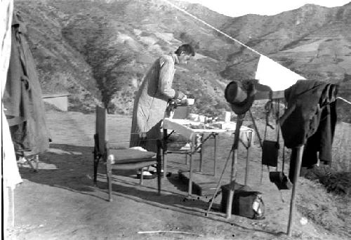 Chinese man preparing food at table, mountain background