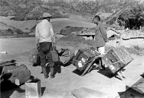 Chinese men with supplies, village in background