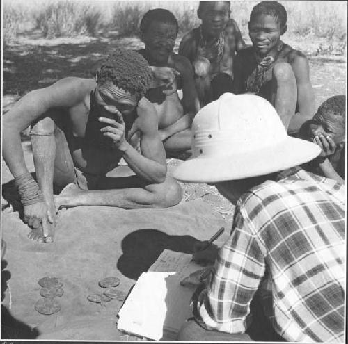 "Oracle disk": Men practicing oracle disc divination, with Lorna Marshall taking notes