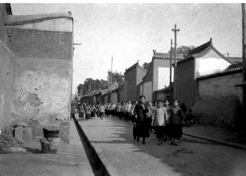 Group of chinese girls holding hands walking along street