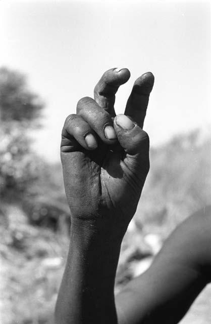 Person demonstrating the hunting hand signal for a hartebeest, seen from the front