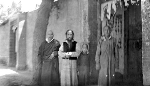 Three men and a boy standing by wall