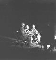 Lorna Marshall, John Marshall, and Laurence Marshall sitting by a fire