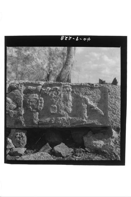 Sculptured lintel, close up of sculpture with glyphic stones in hilltop milpa.