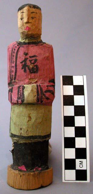 Figurine, carved, standing female, pink, green and black paper applied clothing