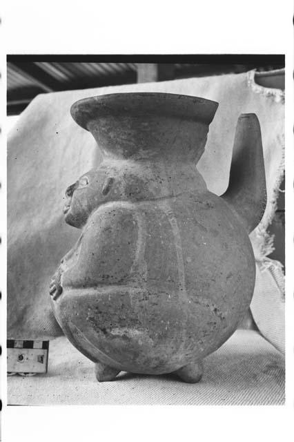 Tetrapodal human female effigy, spouted lost color pottery jar.