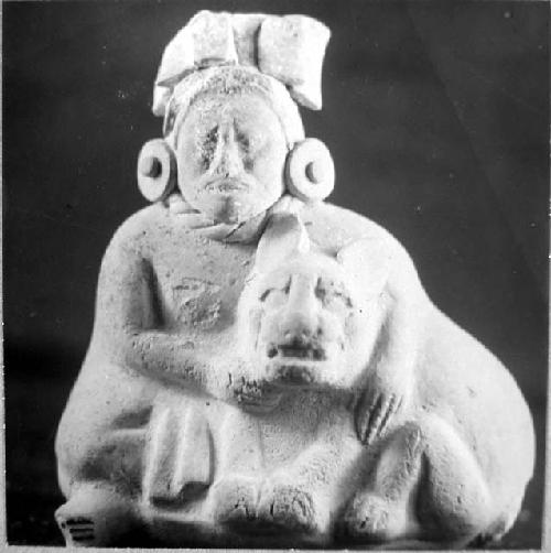 Ceramic figurine, seated human with arms around crouching feline