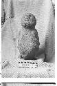 Carved stone seated human effigy figure. Grey igneous stone.