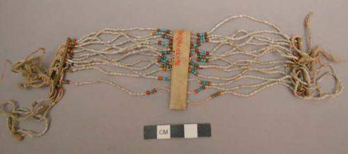 Neck ornament - bone from which hang beads, white & colored, and +