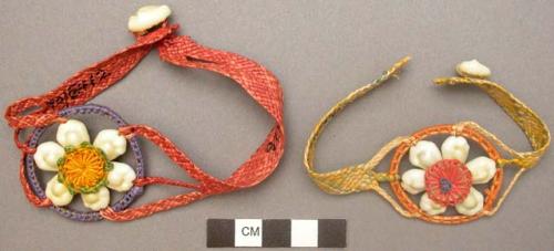 Plaited colored pandamus leaf bracelets, with cowrie shells.