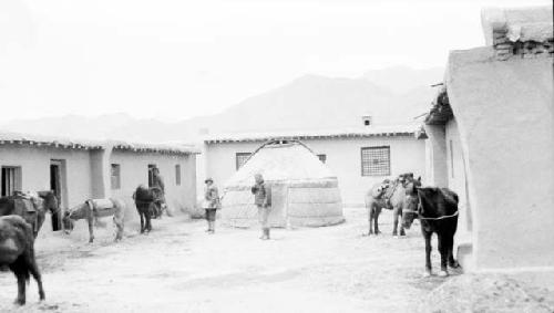 People and ponies by buildings and a tent