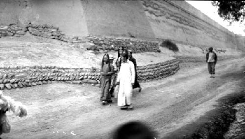 People walking along road by wall