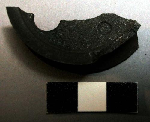 Metal fragment, 1 edge grooved, rounded, pulley?, perforated