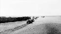 Caravan of camels through desert near wall