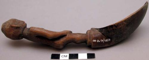 Wooden spoon, handle carved in human effigy: hands resting on flexed knees, lump
